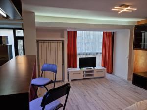een woonkamer met een televisie en een tafel en stoelen bij Nerva Traian Studio in Boekarest