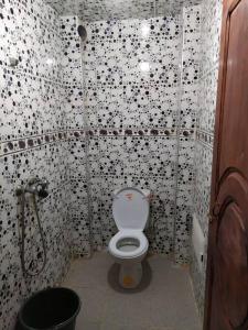 a bathroom with a toilet with black and white tiles at Logement entier appartement in Erfoud