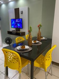 a dining room with a table and yellow chairs at Condomínio manguezal, Apartamento 07 in Porto De Galinhas