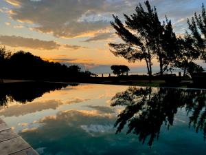 una piscina de agua con una puesta de sol en el fondo en Lagoon Suites e Gastronomia, en Laguna