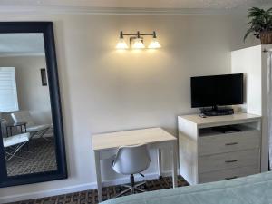 a bedroom with a desk with a television and a mirror at Baechtel Creek Inn, Ascend Hotel Collection in Willits