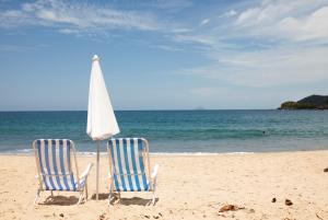 dos sillas y una sombrilla en una playa en Refúgio Toque Toque Chalés, en Toque Toque Grande