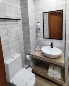 a bathroom with a sink and a toilet and a mirror at Syrtaki Hotel in Ofrínion