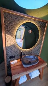 uma casa de banho com um espelho redondo e um lavatório em Luzada - Glamping Burbujas Galicia em Juances