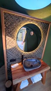 La salle de bains est pourvue d'un miroir rond et d'un lavabo. dans l'établissement Luzada - Glamping Burbujas Galicia, à Juances