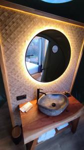 La salle de bains est pourvue d'un lavabo et d'un miroir circulaire. dans l'établissement Luzada - Glamping Burbujas Galicia, à Juances