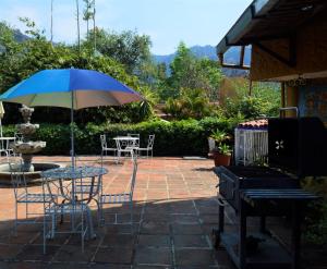 un patio con mesa, sillas y sombrilla en Casa Centeopan, en Amatlán