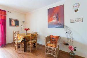 a dining room with a table and chairs and a painting at Cosy apartment with terrace in Alcabideche