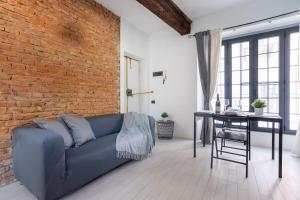 a living room with a blue couch and a brick wall at CENTRO STORICO • Wi-Fi, Netflix e Terrazzo in Pavia