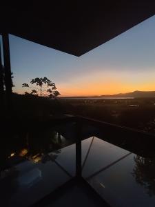 einen Blick auf den Sonnenuntergang von einem Fenster mit einem Baum in der Unterkunft Casa Buda - Garopaba - SC in Garopaba