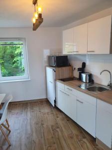 a kitchen with white cabinets and a wooden floor at Naturpanorama in Gleiszellen-Gleishorbach