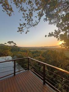 een houten terras met de zonsondergang op de achtergrond bij Casa Buda - Garopaba - SC in Garopaba