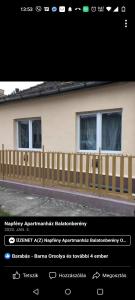 a picture of a house with a wooden fence at Napfény Apartmanház Balatonberény in Balatonberény