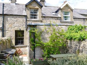 an old stone house with a garden in front of it at Langcliffe Lock Cottage in Stainforth