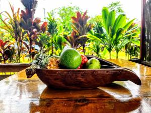 a wooden bowl of fruit on a wooden table at TAHITI - Fare Matavai Hoe in Taravao