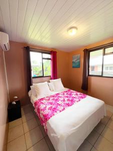 een slaapkamer met een groot wit bed met bloemen erop bij TAHITI - Fare Matavai Hoe in Taravao