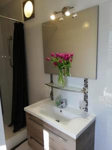 La salle de bains est pourvue d'un lavabo et d'un vase de fleurs roses. dans l'établissement Guesthouse Marie Therese, à Bruxelles