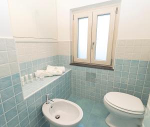 ミノーリにあるSeashell apartmentの青いタイル張りのバスルーム(トイレ、シンク付)