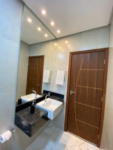 a bathroom with two sinks and a large mirror at Chalés Vista da Serra in Piumhi