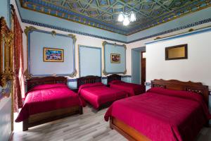 Habitación con 4 camas y sábanas rojas. en Hotel Majestic 1, en Cuenca