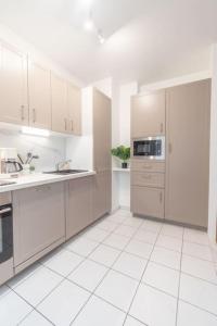 cocina blanca con electrodomésticos blancos y suelo de baldosa blanca en Le Chaleureux-T2-47m2-Disney, en Serris