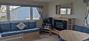 a living room with a blue couch and a tv at Golden Sands Pine Drive 53, 3 Bedrooms & Wi-fi in Mablethorpe