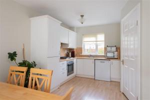 uma cozinha com armários brancos e uma mesa e cadeiras em 2 Cosy Bedrooms in a 3 Bed Home em Tyrrelstown