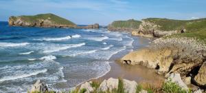a view of a beach with rocks and the ocean at Apartamentos Les Texuques II in Nueva de Llanes