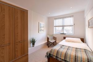 a bedroom with a bed and a wooden cabinet at The Bolthole in Aldeburgh