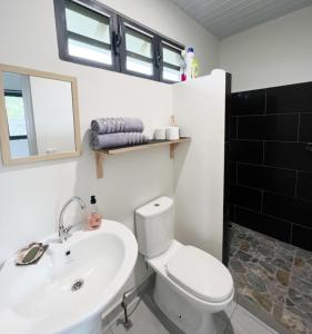 een badkamer met een wit toilet en een wastafel bij TAHITI - Fare Matavai Toru in Taravao