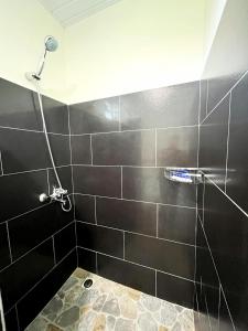 y baño con ducha y pared de azulejos negros. en TAHITI - Fare Matavai Toru, en Taravao