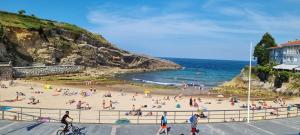 a group of people on a beach near the ocean at Apartamentos Les Texuques II in Nueva de Llanes