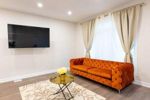 a living room with a orange couch and a tv at Luxury Niagara 3 Bdr Townhouse /Garage in Niagara Falls