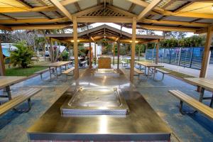 a cafeteria with wooden tables and benches and a grill at Reflections Ferry Reserve - Holiday Park in Brunswick Heads