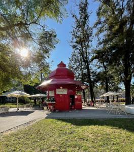 een rode telefooncel in een park met tafels en parasols bij The Swallows Nest in Lissabon