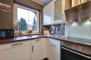 a kitchen with white cabinets and a large window at Ferienwohnung #TIMEOUT in Pfronten