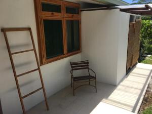 a chair sitting on a porch next to a window at Pension Te Aroha - Te Haumaru in Maatea