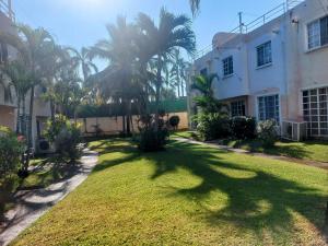 un gran patio con palmeras frente a un edificio en Casa Azur- vista al mar y alberca en Acapulco