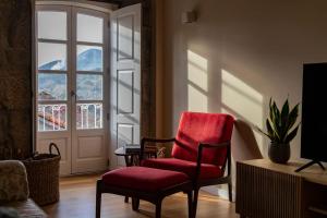 a living room with a red chair and a window at Britelo 1828 - Refúgio na Natureza in Ponte da Barca
