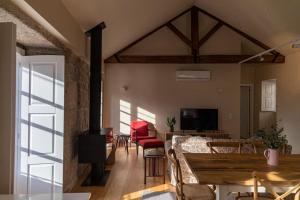 a living room with a table and chairs and a television at Britelo 1828 - Refúgio na Natureza in Ponte da Barca