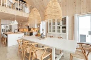 - une cuisine avec une table et des chaises blanches dans l'établissement Chalet le Chardonnay - Spa , Foyers , Accès plage Lac-Jaune, à Chertsey