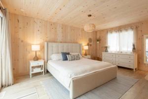 1 dormitorio con 1 cama blanca grande y paredes de madera en Chalet le Chardonnay - Spa , Foyers , Accès plage Lac-Jaune, en Chertsey