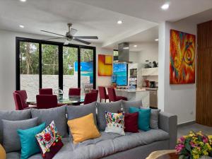uma sala de estar com um sofá cinzento com almofadas coloridas em Casa Debra em Puerto Morelos