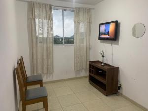 sala de estar con TV, silla y ventana en Hospedagem Reserva da Praia, en Recreio dos Bandeirantes