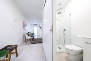 une salle de bain blanche avec toilettes et douche dans l'établissement Casa da Candida one place, many things, à Nazaré 25 autres photos