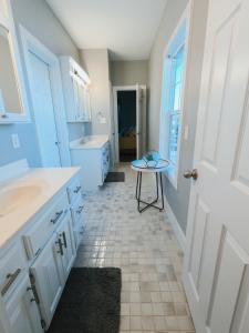 a white bathroom with a sink and a table at Modern, 3 BR Private House within Walking Distance to the Beach! in Gulf Shores