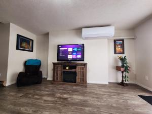 a living room with a flat screen tv and two chairs at Ocean's Edge Suite in Campbell River