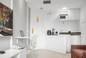 a white living room with a couch and a kitchen at Hotel Vila Olimpia Cozinha Piscina Academia in Sao Paulo