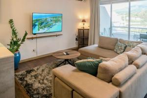 a living room with a couch and a tv on a wall at Grand Large - Premium suite in Papeete