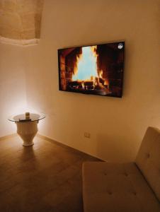 a living room with a fireplace and a tv on the wall at Antica Dimora in Lizzano